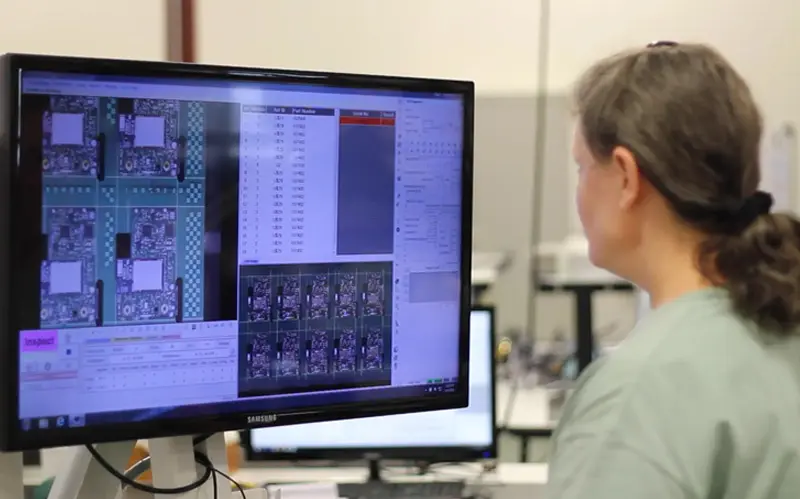 an electronic assembly worker reviewing and testing a PCB