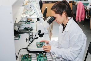 Close up of a female technician assembling a printed circuit board microchip. 