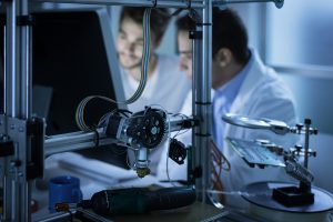 Two male engineers looking at a computer screen in an electronics manufacturing facility. 