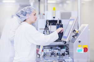 Picture of a female technician touching a screen at a medical manufacturer. 