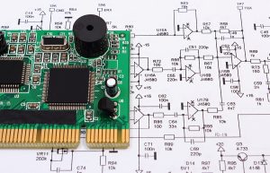 Printed circuit board with electrical components lying on construction drawings. 