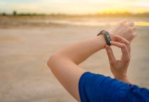 Close up of a woman touching the screen of her wearable fitness device on her wrist. 