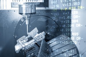 Closeup of a machine cutting an aerospace part with the g-code in the background.