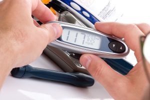 Closeup of a hand holding a diabetes glucose finger monitor. 